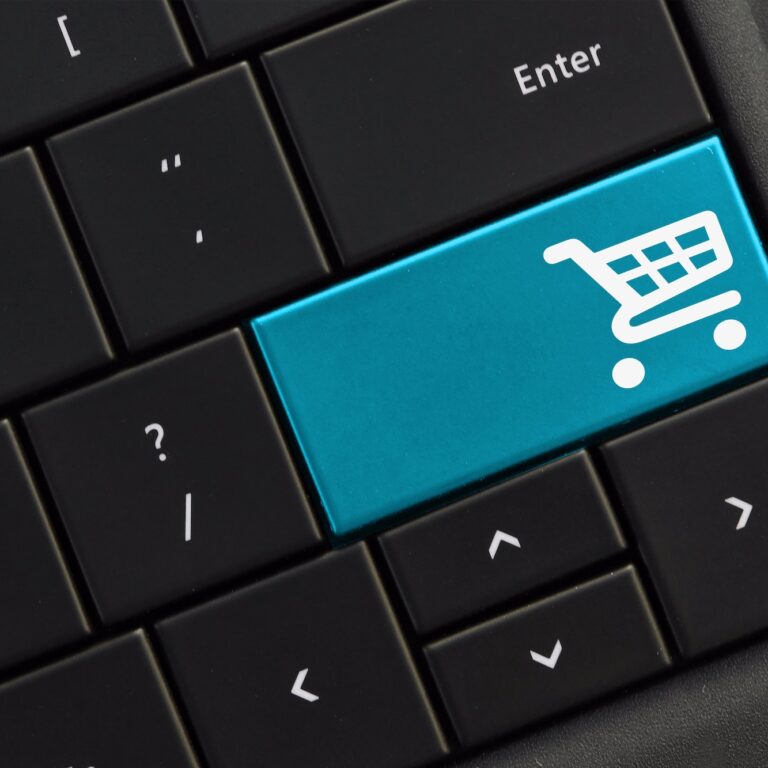 Black computer keyboard with blue shopping cart button. Buying purchasing shopping online concept